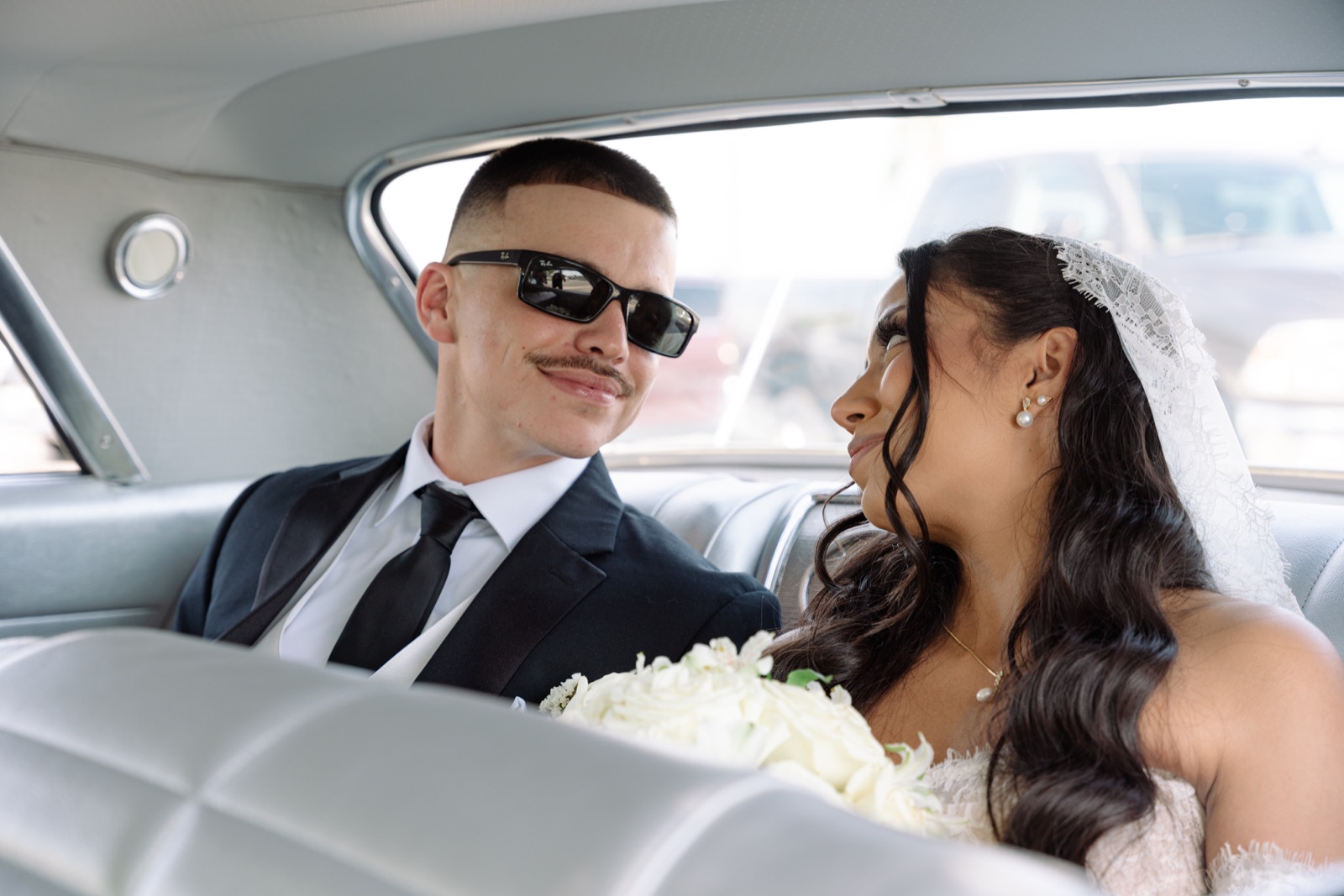 Novios compartiendo un momento íntimo dentro de un carro clásico