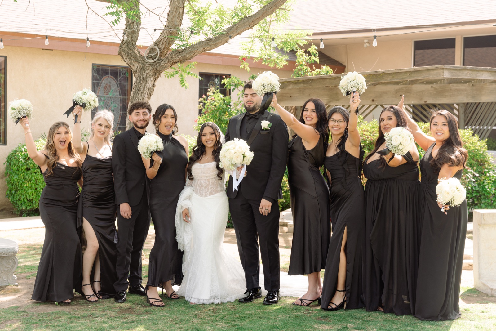 Novios con su corte de boda sosteniendo ramos blancos